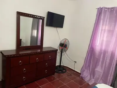 a room with a dresser with a mirror and a fan at Kasita del sol boca chica in La Caleta