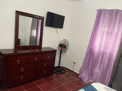 a bedroom with a dresser with a mirror and a fan at Kasita del sol boca chica in La Caleta