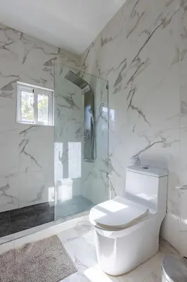 a bathroom with a toilet and a glass shower at Luxurious Home with Pool! in San Felipe de Puerto Plata