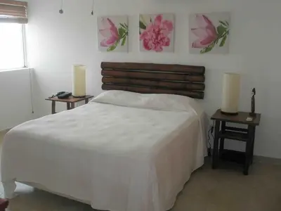 a bedroom with a white bed and two tables with candles at Lovely apartment by the Caribbean in Bayahibe