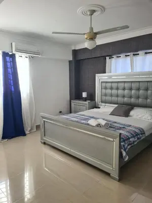 a bedroom with a large bed with blue curtains at Oasis Colonial in Santo Domingo