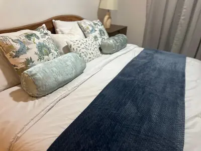 a bed with blue and white pillows on it at Villa Paz in La Romana