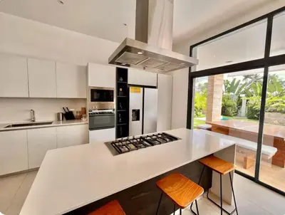 a kitchen with white cabinets and a counter with orange chairs at 5 Bedroom Villa With Daily Housekeeping in Las Terrenas