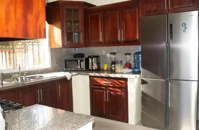 a kitchen with wooden cabinets and a stainless steel refrigerator at Casa de alquiler FIGARO in Villa Clara