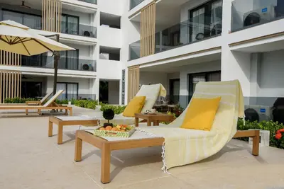 a hotel patio with chairs and a table and an umbrella at Bran new condo with pool access in Punta Cana