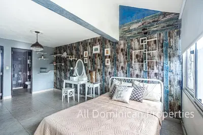 a bedroom with a bed in a room with a wall ofieval at Unusual Artist's Loft with jacuzzi and Roof Terrace in Sosúa