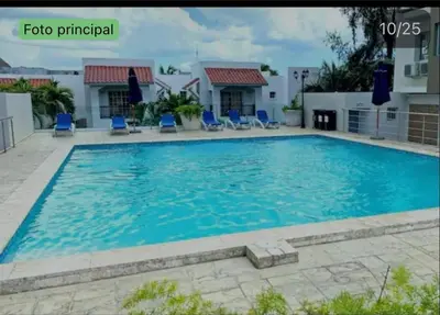 a large swimming pool with blue chairs in front of a building at Vista al mar in Boca Chica