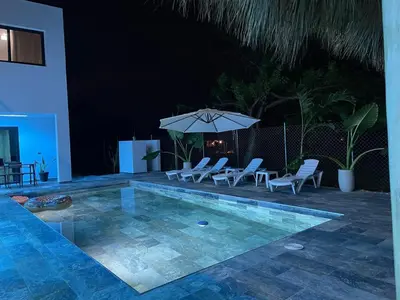 a swimming pool with chairs and an umbrella at Apartamento Entre Playas 1 - 3 pax, 4 min de la playa in Las Galeras