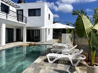 a pool with white chairs and an umbrella next to a house at Apartamento Entre Playas 1 - 3 pax, 4 min de la playa in Las Galeras