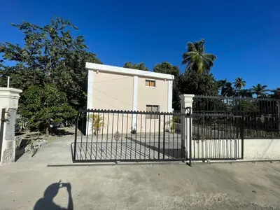a gate in front of a white house with palm trees at Loft's R&L in Juan de Herrera