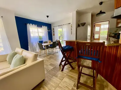 a living room with a white couch and a kitchen at Un Lugar Único y Céntrico RD Los Corales in Punta Cana