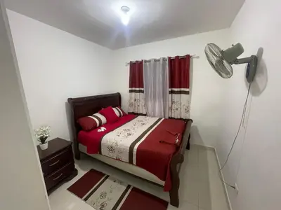 a small bedroom with a bed with red and white sheets at Antare ll edificio 52 A3 in Santo Domingo