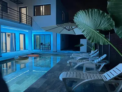 a swimming pool with white chairs and an umbrella at Apartamento Entre Playas - 5 pax, 4 min de la playa in Las Galeras