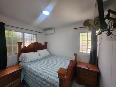 a bedroom with a bed and two windows at Apartment in front of beach, AC, Wifi, Hot Water in Paraíso