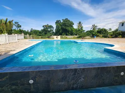 a swimming pool with blue water and a beach at Bella Villa room with kitchenette, pool and close to the beach in Las Galeras in Las Galeras