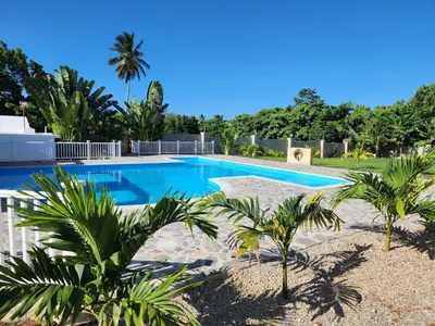 a swimming pool with palm trees around it at Bella Villa room with kitchenette, pool and close to the beach in Las Galeras in Las Galeras