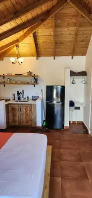 a kitchen with a white bed and a black refrigerator at Bella Villa room with kitchenette, pool and close to the beach in Las Galeras in Las Galeras