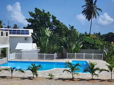 a villa with a swimming pool and palm trees at Bella Villa room with kitchenette, pool and close to the beach in Las Galeras in Las Galeras