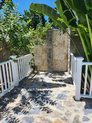 a white fence next to a building with a tree at Bella Villa Apart for 2 with kitchen pool and close to the beach in Las Galeras