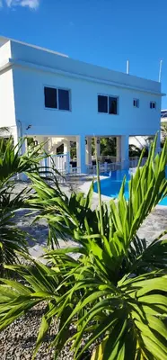a white building with a palm tree in front of it at Bella Villa Apart for 2 with kitchen pool and close to the beach in Las Galeras
