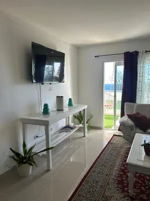 a living room with a white table and a tv at Gran Apartamento frente al mar in La Francia