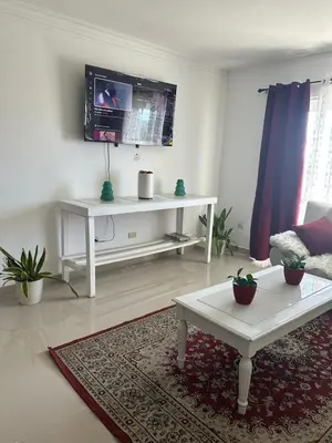 a living room with a white table and a tv at Gran Apartamento frente al mar in La Francia