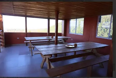 a room with benches and tables in a room with windows at Vista Montaña Jimenoa de la Rosa in Jarabacoa