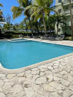 a swimming pool with blue water and palm trees at Vista al Caribe in La Francia