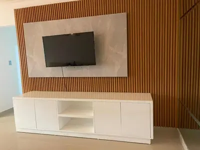 a white entertainment center with a television on a wall at Vista al Caribe in Los Mameyes