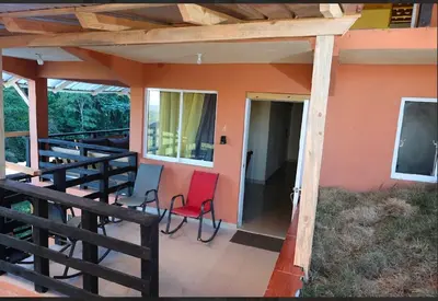 a porch of a house with two red chairs at Vista Montaña Jimenoa De La Rosa in Jarabacoa