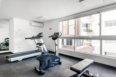 a gym with treadmills and ellipticals in a room with a window at Charming space in the city center in Santo Domingo