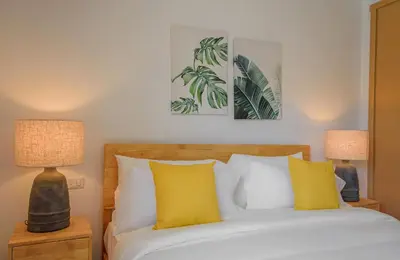 a bedroom with a bed with yellow pillows and two lamps at Amazing pool views apartment in Playa Bavaro in Punta Cana