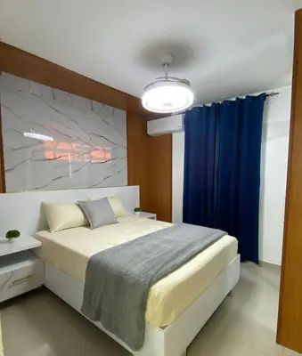 a bedroom with a large bed with blue curtains at Modern, Unique And Stylish 1 Bedroom Apartment in San Pedro de Macorís