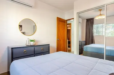 a bedroom with a large bed and a mirror at Chic Urban Retreat with Pool, Gym, & Free Parking in Santiago de los Caballeros
