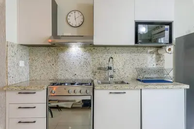 a kitchen with white cabinets and a clock on the wall at La Condesa del Vergel in Santo Domingo