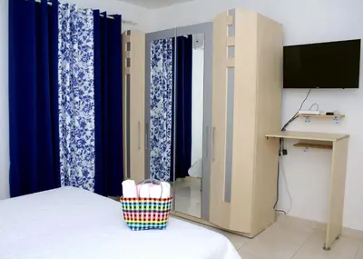 a room with a bed with blue curtains and a television at RGgrup in Pantoja