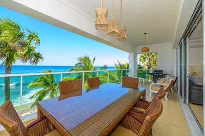 a dining room with a table and chairs and the ocean at Bluegreen Oceanfront Condo at Laguna Beach in Sosúa