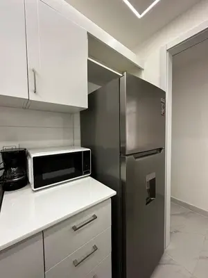 a kitchen with a stainless steel refrigerator and white cabinets at Santo Domingo Este Stylish Condo in San Isidro