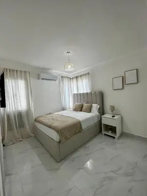 a white bedroom with a bed and a night stand at Santo Domingo Este Stylish Condo in San Isidro