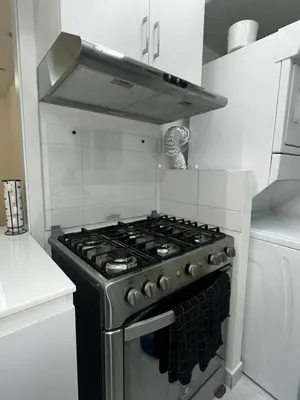 a stove top oven in a white kitchen at Santo Domingo Este Stylish Condo in San Isidro