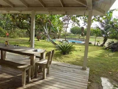 a wooden deck with a table and chairs and a pool at Villa Bianca - BEACHFRONT with Pool in Sosúa