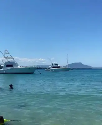 a person swimming in the water with two boats at Beautiful villa in the Caribbean! in Sosúa