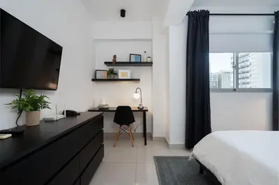 a bedroom with a bed and a desk with a television at Armonia 17 suites by Yellowkey in Santo Domingo