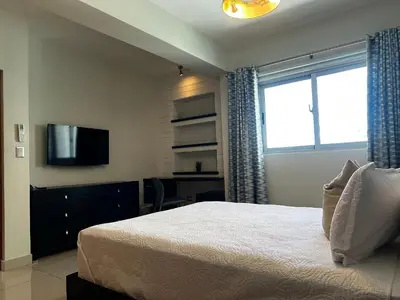 a bedroom with a bed and a desk and a television at Armonia 17 suites by Yellowkey in Santo Domingo