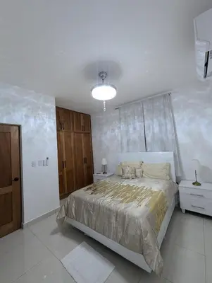 a white bedroom with a bed and a window at Marbella in San Felipe de Puerto Plata