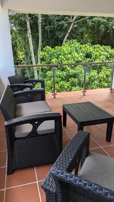 a patio with four chairs and tables and trees at Spacious Apartment w Pool in Las Terrenas