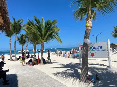 a group of people on a beach with palm trees at Cocotal 2beds apartament Golf Course Melia Beach PC RD in Punta Cana