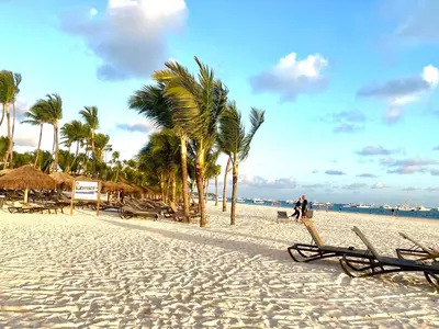 a beach with chairs and palm trees and the ocean at Cocotal 2beds apartament Golf Course Melia Beach PC RD in Punta Cana