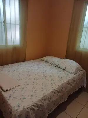 a small bed in a bedroom with two windows at Dona Beba Guesthouse in La Caleta