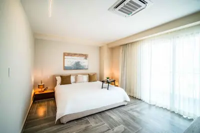 a bedroom with a white bed and a large window at Aston Rubi City Suites in Santo Domingo